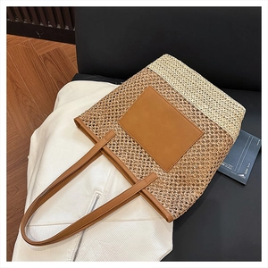 Detail of two-tone woven straw tote bag with brown leather pocket and straps