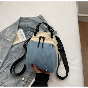 Detail of a mini canvas denim bag with blue patchwork and woven carry handles