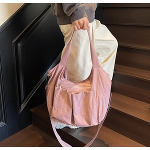 Close-up of pink nylon tote bag showing front pockets and adjustable crossbody strap