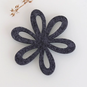 Macro shot of dark grey felt coaster with hexagonal cutout flower design and fiber texture