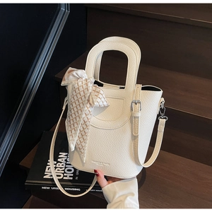Dettaglio borsa a secchiello bianca in pelle litchi con foulard a scacchi su scale di legno