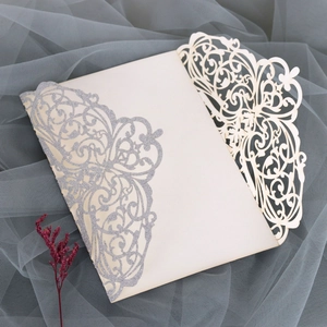 Detailed laser cut ivory wedding invitation with elegant silver glitter floral patterns