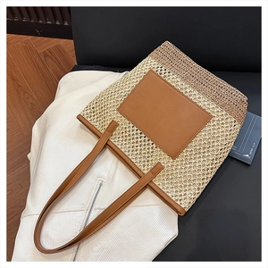 Detail shot of woven straw texture and brown leather strap on a large tote bag
