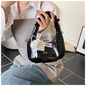 Detail of black pleated handle handbag with lace bow and pearl charm ornament