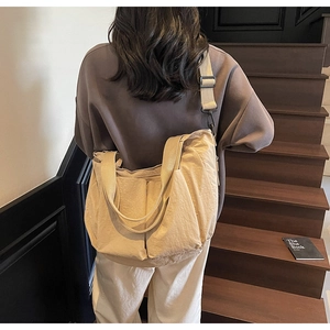 Detail view of beige canvas tote bag with adjustable wide strap and symmetric pockets