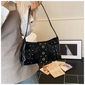 Détail du sac à bandoulière en cuir verni noir avec rivets argentés et œillets en métal