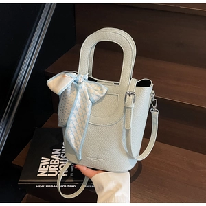 Dettaglio borsa a secchiello azzurra con foulard di seta e texture pelle litchi pregiata