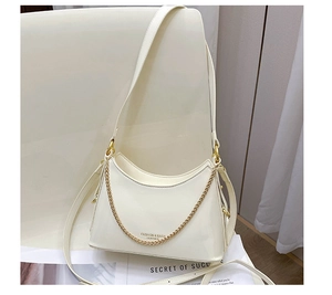 Detailed close-up of cream leather bucket bag with gold chain and fashion lettering