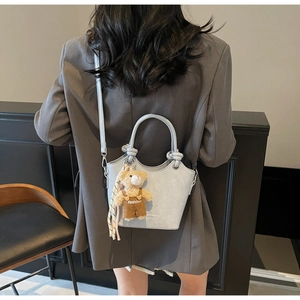 Detail of light blue crocodile embossed bucket bag with a cute bear charm pendant