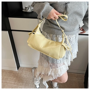 Détail de la texture en cuir verni brillant jaune pâle et de la bandoulière de ce sac à main