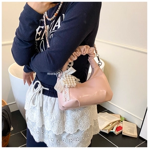 Detail of pink ruffled handle handbag with white lace bow and pearl charm ornament
