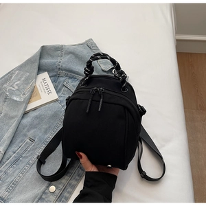Detail of black mini backpack featuring a unique black and white braided top handle