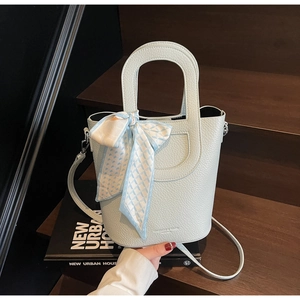 Dettaglio della borsa a secchiello verde menta con trama a litchi e foulard a scacchi