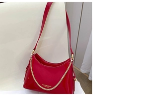 Close-up of bright red patent leather bucket bag with gold chain and printed logo