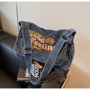 Close-up of vintage blue denim bag with yellow and red embroidery on black books