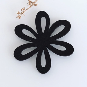 Detailed view of a black flower-shaped felt coaster with laser-cut hollow petal design