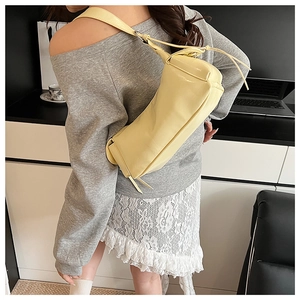 Vue détaillée d'un sac à bandoulière en similicuir jaune brillant porté par un modèle