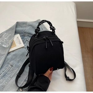 Detail view of black waterproof backpack featuring contrast woven handle and metal zipper