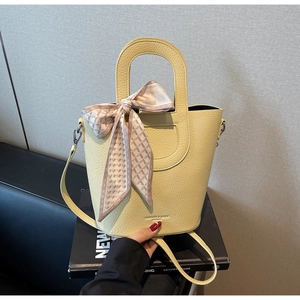Dettaglio borsa a secchiello in pelle gialla con foulard di seta a motivi geometrici