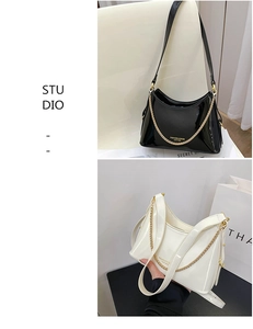 Detailed close-up of glossy leather hobo bag with gold chain and branded lettering