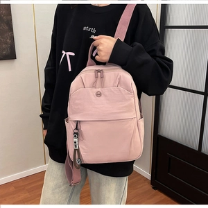 Detailed side view of pink nylon backpack with ergonomic straps and smile charm