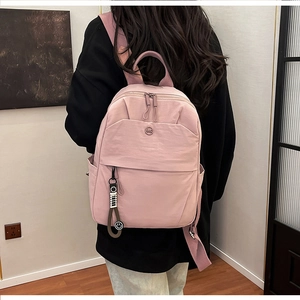 Detail view of the pink stylish backpack with double zippers and metal logo charm