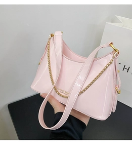 Detail view of pink patent leather hobo bag with glossy finish and gold chain strap