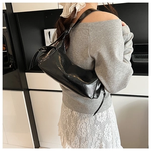 Détail du sac à bandoulière en cuir verni noir brillant avec fine bandoulière rétro chic