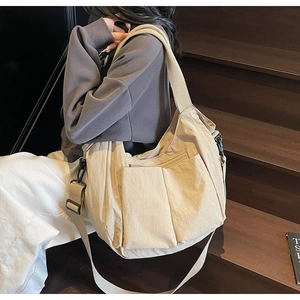 Detail of beige large capacity tote bag with side pleats and adjustable strap