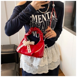 Détail du sac à main rouge plissé avec nœud en perles et bandoulière en chaîne
