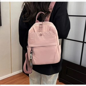 Detail of pink nylon backpack with circular logo and trendy smile pendant on a model