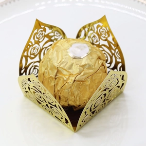 Detail of laser-cut gold rose paper candy box with a spherical chocolate inside