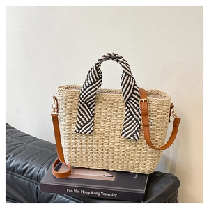 Détail d'un sac cabas en paille tissée avec foulard rayé et bandoulière en cuir