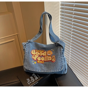 Detail of blue denim messenger bag with colorful Lookin' Good embroidery and star pattern