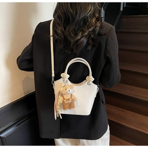 Detail of white crocodile pattern bucket bag with cute bear charm and knot handle
