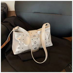 Gros plan d'un sac à bandoulière beige avec des clous métalliques argentés sur cuir