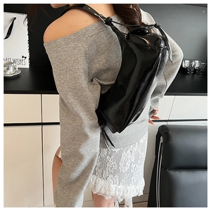 Détail d'un sac hobo noir brillant en similicuir poli avec un design élégant et épuré