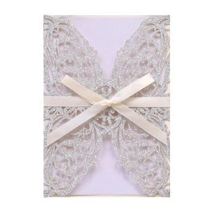 Detail of silver glitter laser cut wedding invitation with elegant cream satin ribbon bow