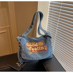 Detailed embroidery of star and text on a vintage blue denim crossbody tote bag