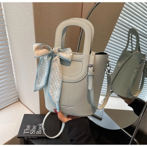 Dettaglio della borsa a secchiello azzurra con motivo litchi, foulard e riflesso