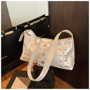 Gros plan d'un sac à bandoulière blanc crème avec des rivets et une large bandoulière