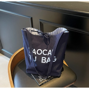 Détail du cabas en toile bleu marine avec grandes lettres imprimées et doublure en vichy