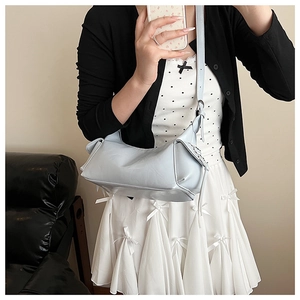 Détail d'un sac à bandoulière bleu clair avec un nœud papillon élégant et une sangle