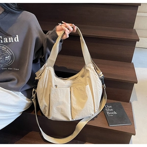 Detailed view of the beige canvas tote bag with multiple pockets on dark wooden stairs