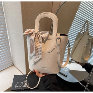 Dettaglio della borsa a secchiello off-white con foulard in seta sul manico