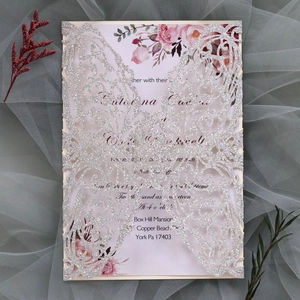 Detail view of laser-cut butterfly wedding invitation with silver glitter and pink floral