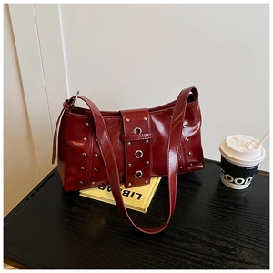 Gros plan d'un sac rétro bordeaux avec rivets métalliques et œillets sur une table en bois