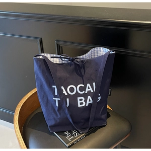 Détail du sac cabas en toile bleu foncé avec texte blanc et doublure à carreaux