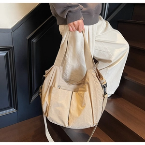 Close-up of beige nylon tote bag with multi-pocket design and adjustable strap