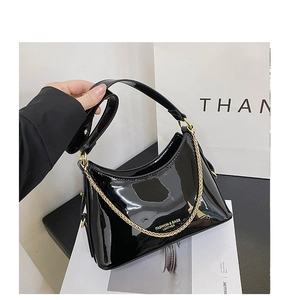 Detail of glossy black patent leather hobo bag featuring gold logo and chain strap